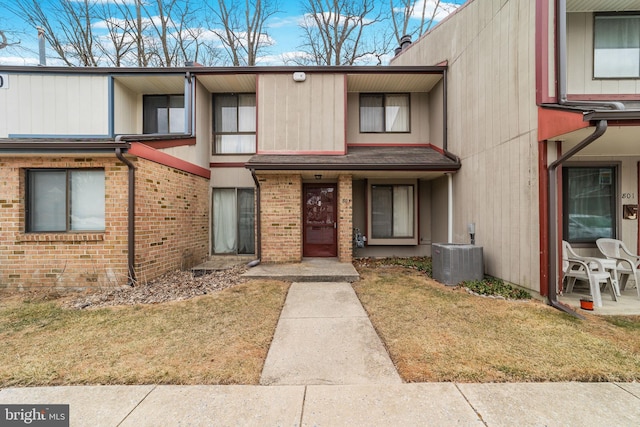 townhome / multi-family property featuring central AC and brick siding