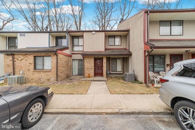 multi unit property featuring a chimney, central AC, and brick siding