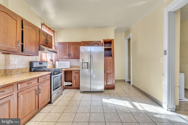 kitchen featuring under cabinet range hood, stainless steel appliances, light countertops, decorative backsplash, and brown cabinetry