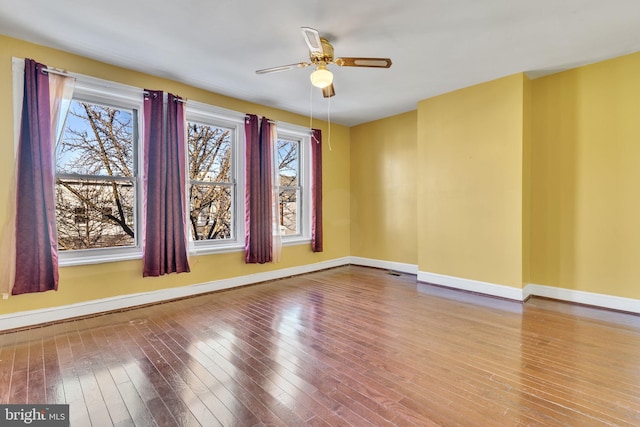 empty room featuring ceiling fan, wood finished floors, and baseboards