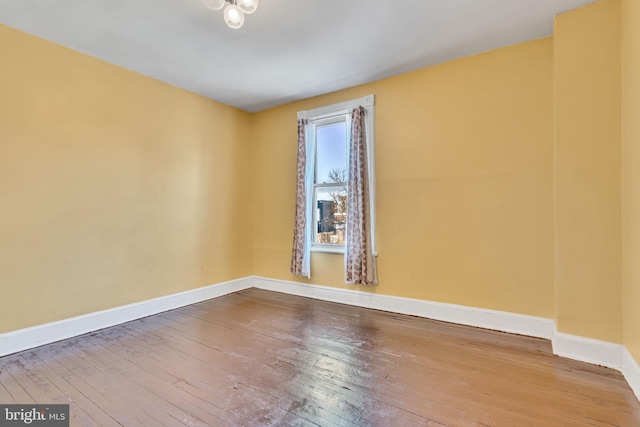 spare room with baseboards and wood finished floors