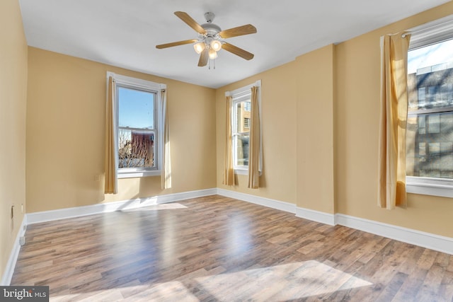 empty room with baseboards, a ceiling fan, and light wood-style floors