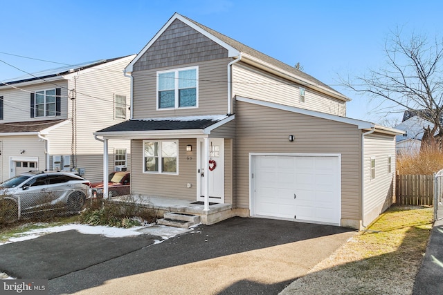 view of front of home with a shingled roof, a porch, fence, a garage, and driveway