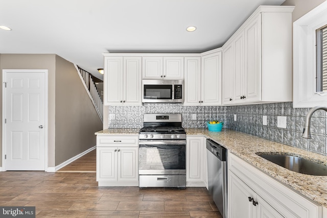 kitchen featuring dark wood-type flooring, tasteful backsplash, stainless steel appliances, and a sink