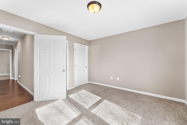 unfurnished bedroom featuring visible vents, carpet, attic access, and baseboards