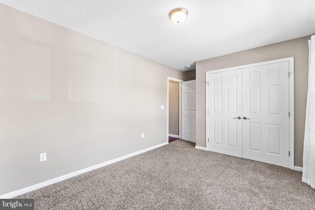 unfurnished bedroom with carpet, a closet, and baseboards