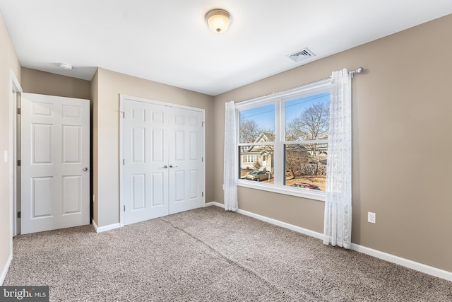 unfurnished bedroom featuring carpet flooring, visible vents, and baseboards