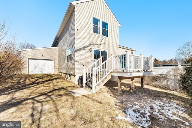 rear view of house with a garage, fence, and a deck