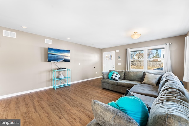 living room with baseboards, visible vents, and wood finished floors