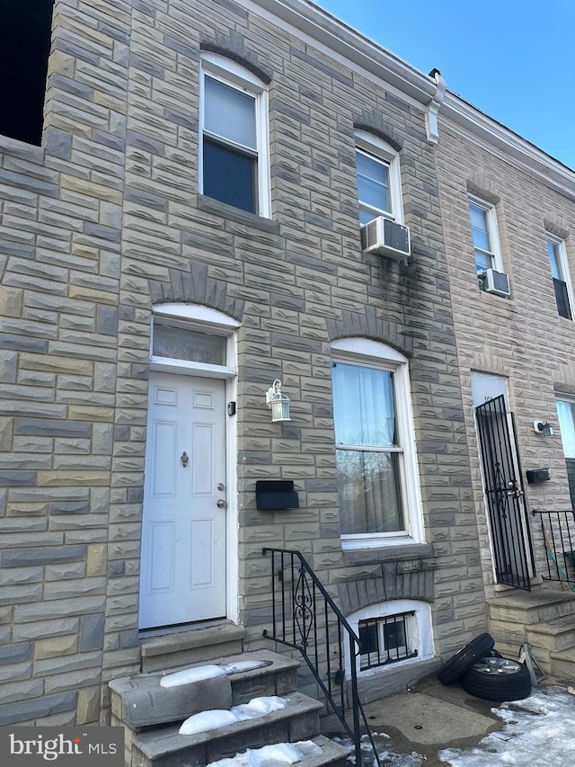 view of front of property featuring entry steps, stone siding, and cooling unit