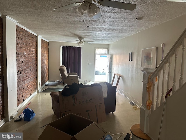 interior space with a ceiling fan, brick wall, stairs, a textured ceiling, and light floors