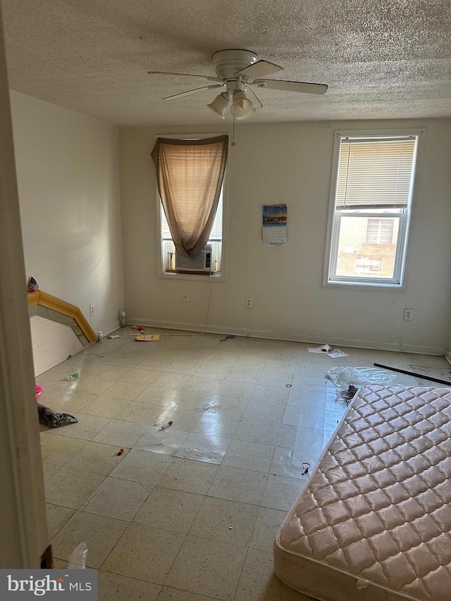spare room with ceiling fan, a textured ceiling, and baseboards