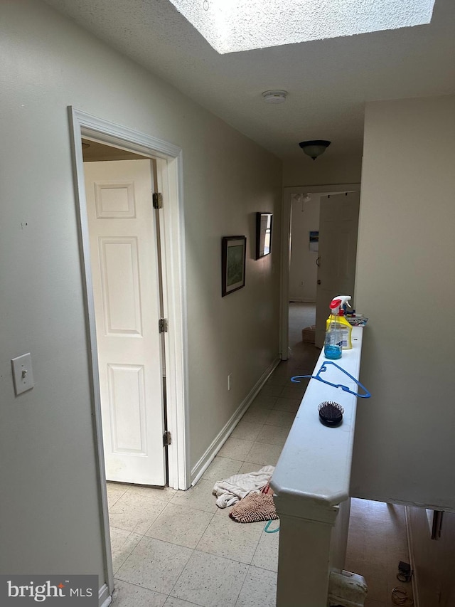 hall featuring light floors and baseboards