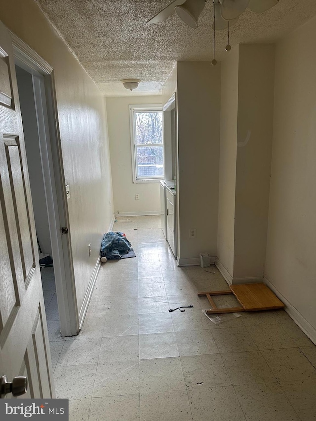 empty room featuring a textured ceiling, washing machine and dryer, and baseboards