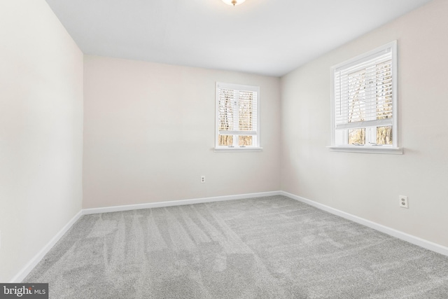 spare room with light colored carpet, plenty of natural light, and baseboards