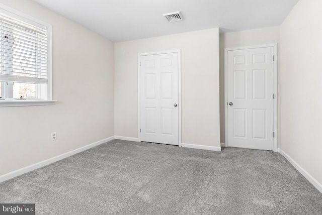 unfurnished bedroom featuring light colored carpet, visible vents, and baseboards