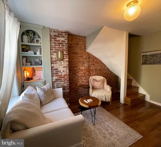 living room with dark wood-style floors, built in features, stairway, brick wall, and baseboards