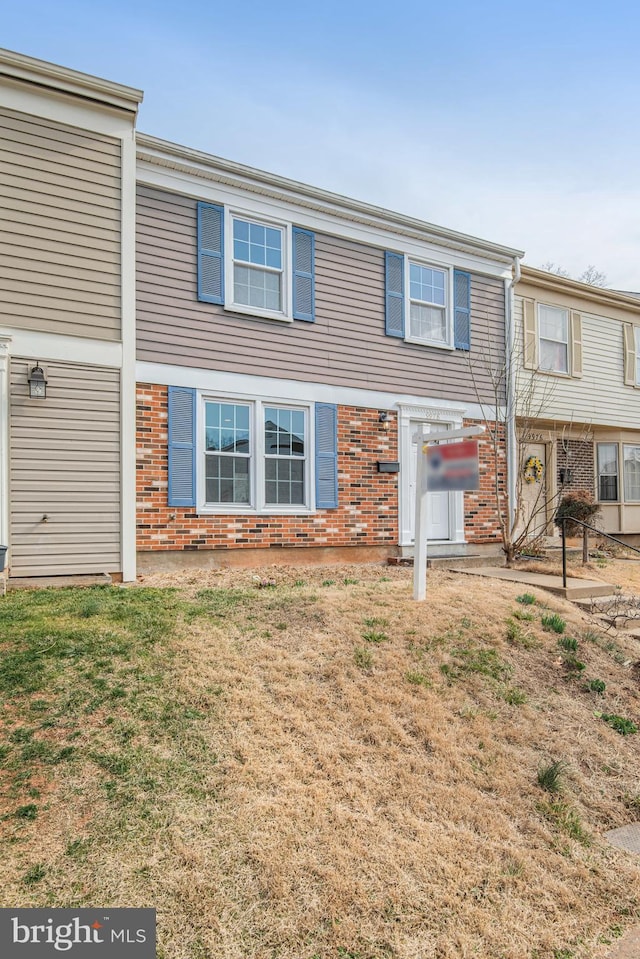 multi unit property with brick siding and a front yard