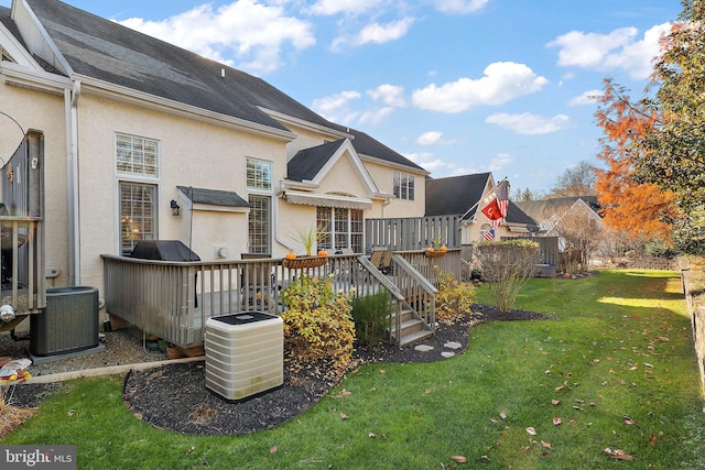 back of property featuring a lawn, a deck, cooling unit, and stucco siding