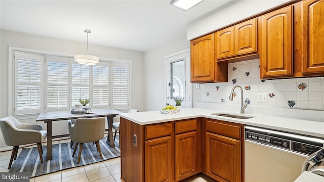 kitchen with dishwasher, light countertops, backsplash, and a sink