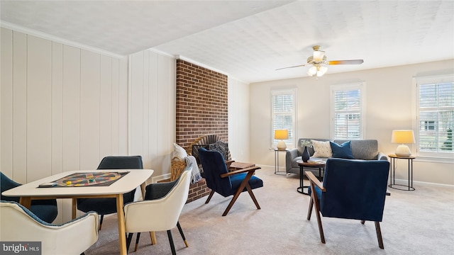 interior space featuring baseboards, light colored carpet, ceiling fan, crown molding, and a fireplace