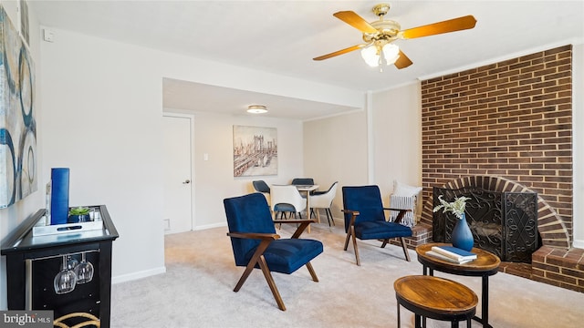 sitting room with a ceiling fan, light colored carpet, a fireplace, and baseboards