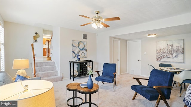 sitting room featuring light colored carpet, visible vents, ceiling fan, baseboards, and stairs