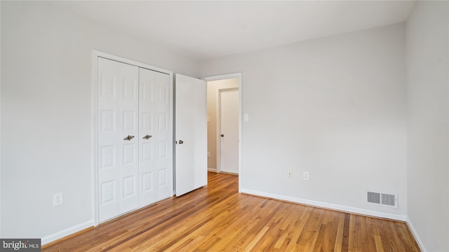 unfurnished bedroom with light wood-style floors, baseboards, visible vents, and a closet