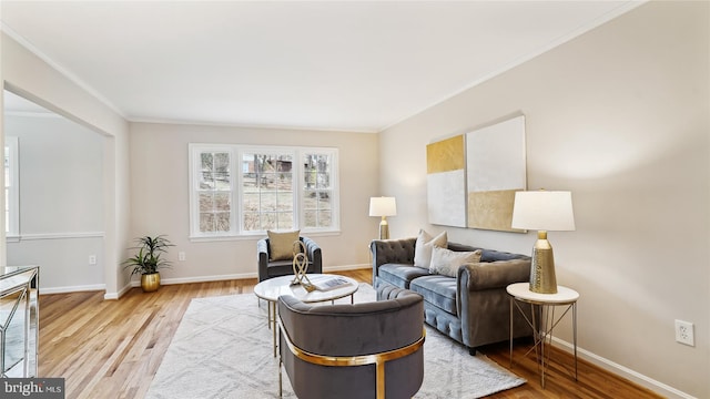 living area featuring ornamental molding, light wood-type flooring, and baseboards