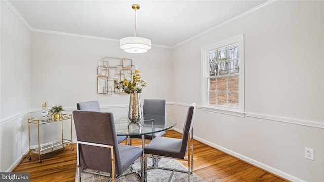 dining space with crown molding, baseboards, and wood finished floors