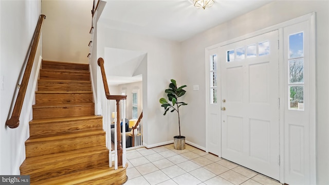 entryway featuring light tile patterned floors, stairway, plenty of natural light, and baseboards