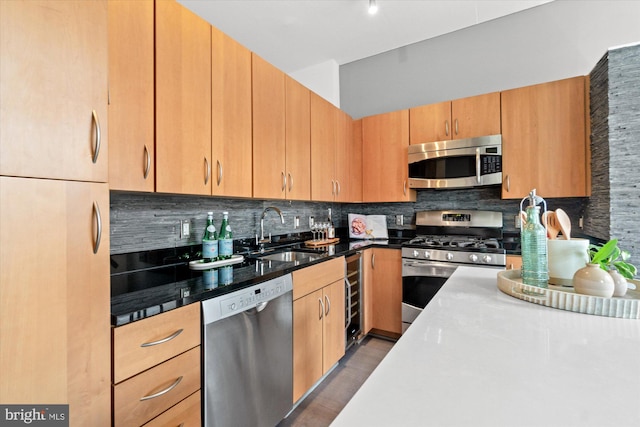 kitchen featuring stainless steel appliances, tasteful backsplash, a sink, dark stone counters, and beverage cooler