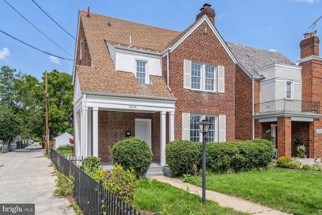 view of front of house featuring a shingled roof, a chimney, fence, and brick siding