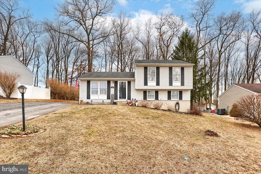 split level home featuring aphalt driveway, central AC, and a front lawn