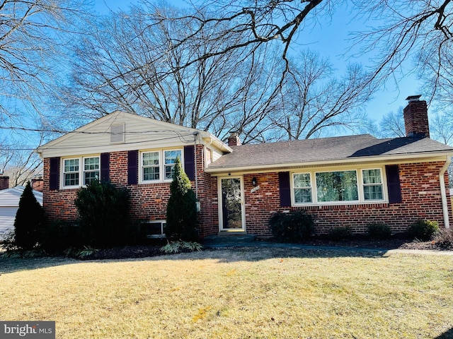 tri-level home with a chimney, a front lawn, and brick siding