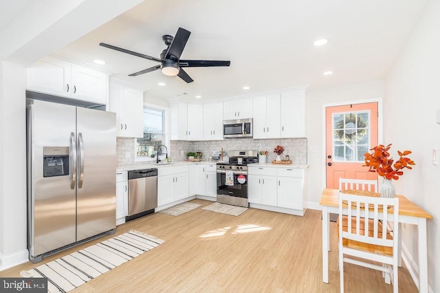 kitchen with light wood finished floors, white cabinetry, appliances with stainless steel finishes, and light countertops