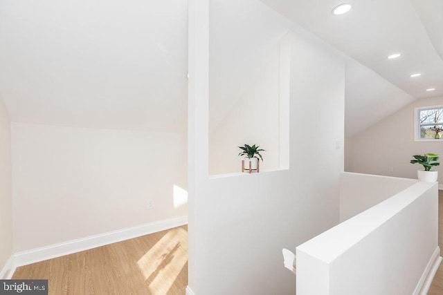 corridor with recessed lighting, wood finished floors, an upstairs landing, baseboards, and vaulted ceiling