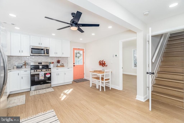 kitchen with decorative backsplash, appliances with stainless steel finishes, light countertops, light wood-style floors, and white cabinetry