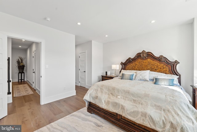 bedroom with baseboards, wood finished floors, and recessed lighting