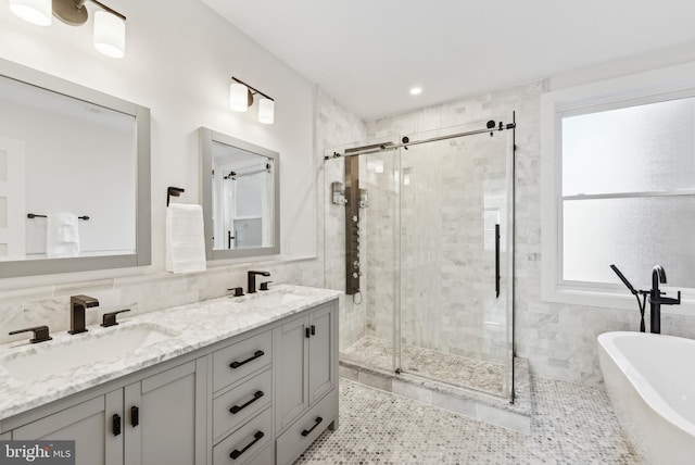 bathroom featuring a freestanding tub, a sink, and tile walls