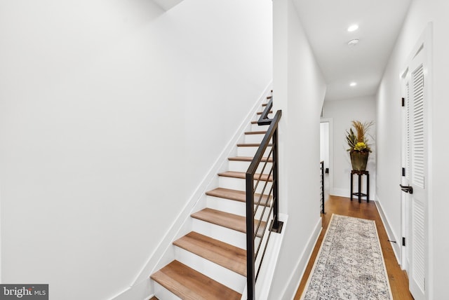 staircase with baseboards, wood finished floors, and recessed lighting