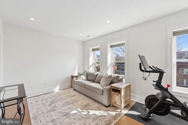 workout room featuring baseboards, recessed lighting, light wood-type flooring, and a healthy amount of sunlight