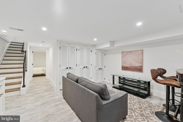 living area featuring light wood-style floors, recessed lighting, visible vents, and stairway