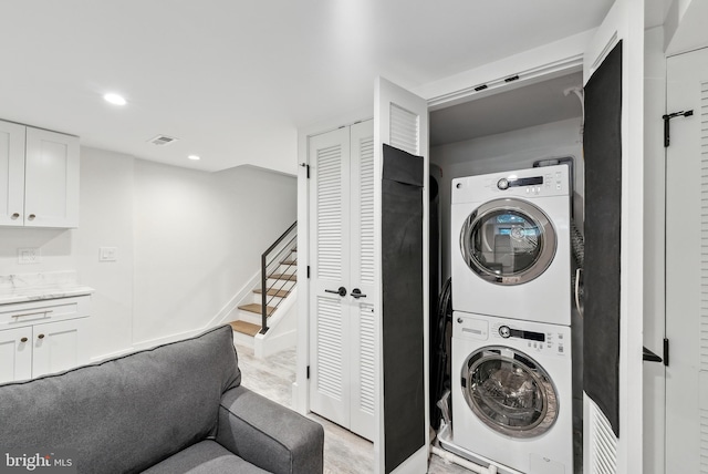 laundry area featuring stacked washer and clothes dryer, recessed lighting, visible vents, light wood-type flooring, and laundry area