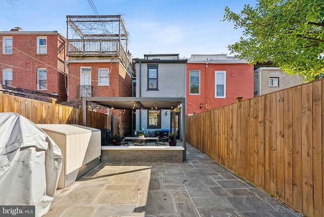 rear view of house with brick siding, fence, and a patio