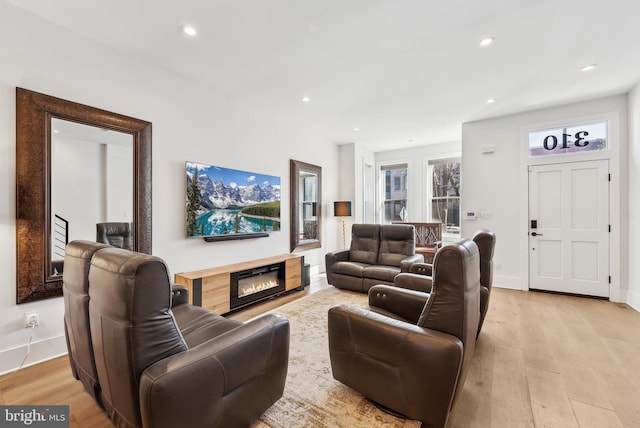 living room with light wood-style floors, recessed lighting, a glass covered fireplace, and baseboards