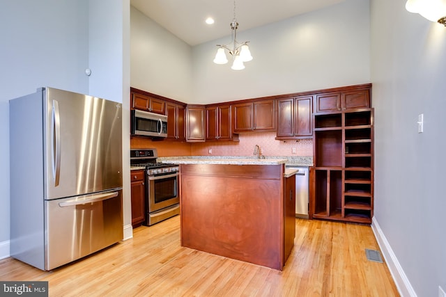 kitchen with decorative light fixtures, light countertops, visible vents, appliances with stainless steel finishes, and a kitchen island