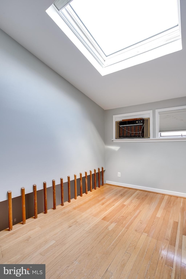 unfurnished room featuring a skylight and wood-type flooring