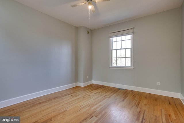 spare room featuring light wood-type flooring, visible vents, ceiling fan, and baseboards