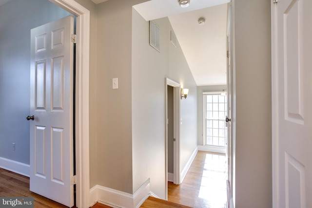 hall featuring visible vents, baseboards, and wood finished floors